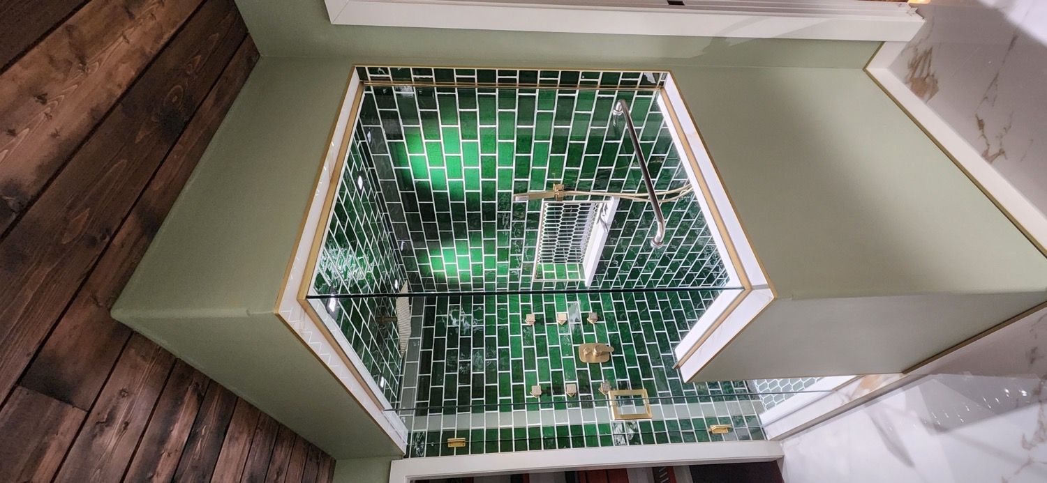 Detailed emerald tile and gold fixtures in the South River Jewel shower